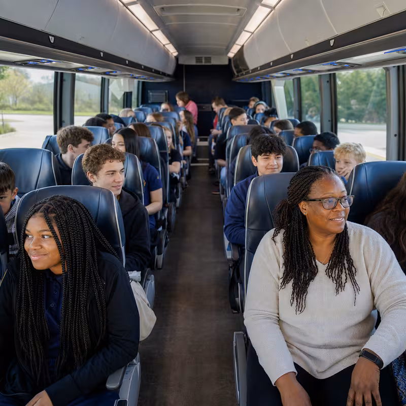 Group boarding a white charter bus for School Transportation transportation in Peoria